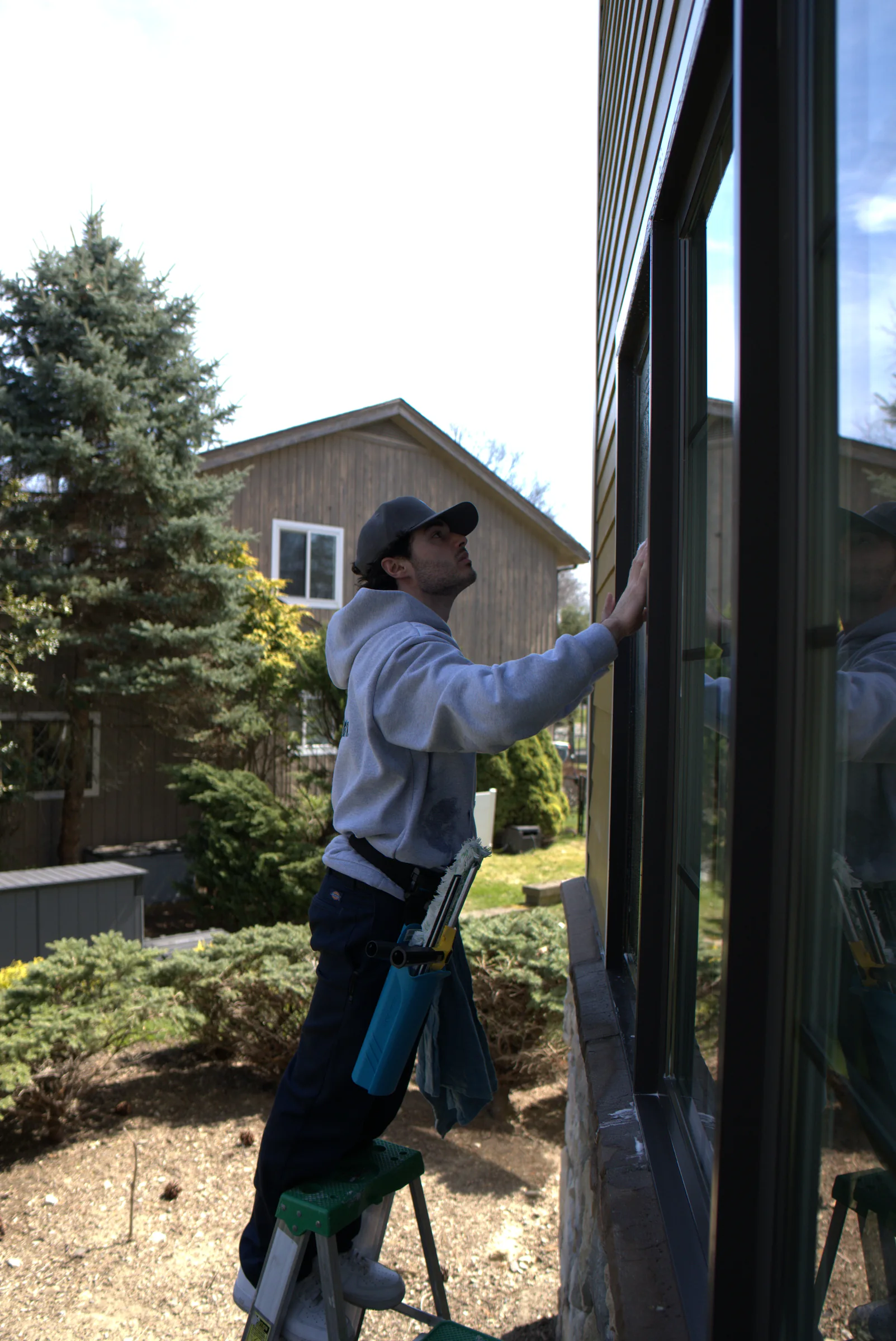 Technician on a ladder cleaning tall exterior glass